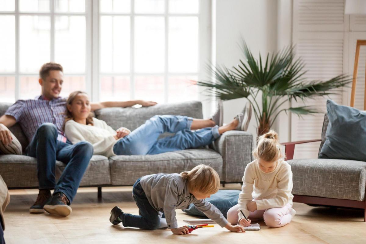 Mum and Dad on couch watching their children play on the floor