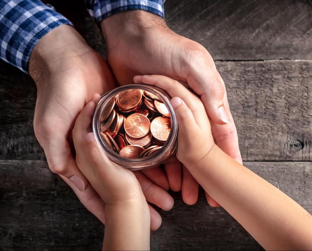 Money in a jar being held by dad and child