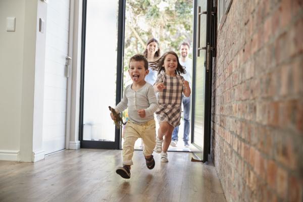 Children running in front door of house with parents behind